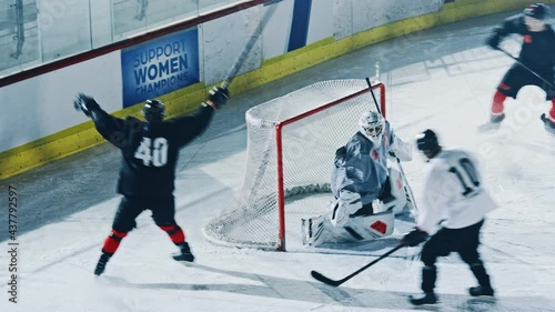 Ice Hockey Rink Arena: Professional Forward Player Masterfully Dribbles, Breaks Defense, Hitting Puck with Stick Scores Goal, Goalie Missed it. Fast, Energetic, Cinematic High Angle Wide Shot photo