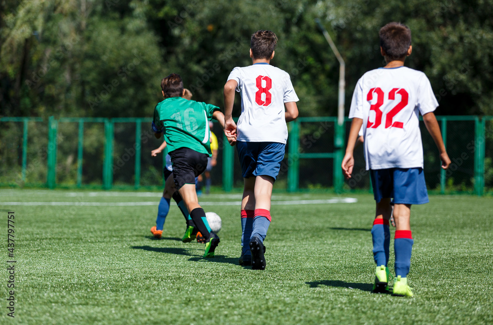 Boys in green sportswear running on pitch. Young footballers dribble and kick football ball in game. Training, active lifestyle, sport Boys in green sportswear running on pitch. Young footballers dribble and kick football ball in game. Training, active lifestyle, sport