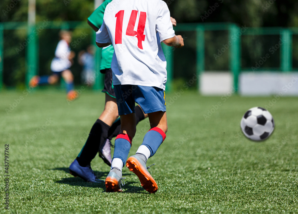 Boys in green sportswear running on pitch. Young footballers dribble and kick football ball in game. Training, active lifestyle, sport Boys in green sportswear running on pitch. Young footballers dribble and kick football ball in game. Training, active lifestyle, sport