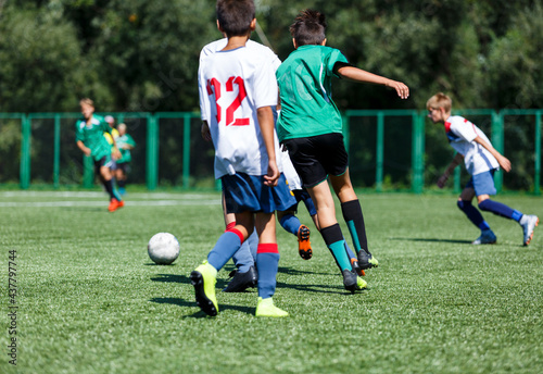 Boys in green sportswear running on pitch. Young footballers dribble and kick football ball in game. Training, active lifestyle, sport 