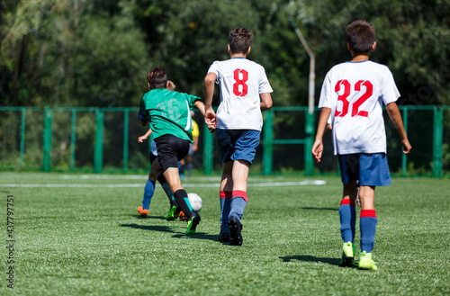 Boys in green sportswear running on pitch.  Young footballers dribble and kick football ball in game. Training, active lifestyle, sport  © Natali