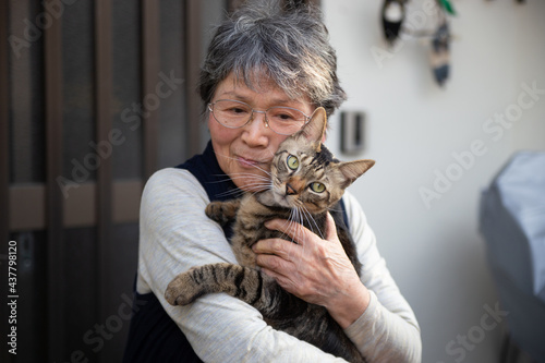 Portrait of an old Asian lady holding a brown patch cat in Japan.