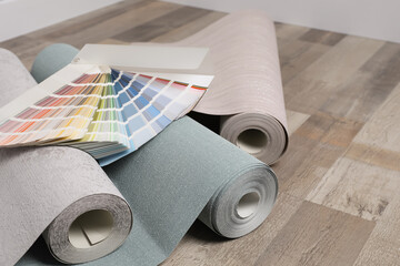 Wall paper rolls and color palette on wooden floor