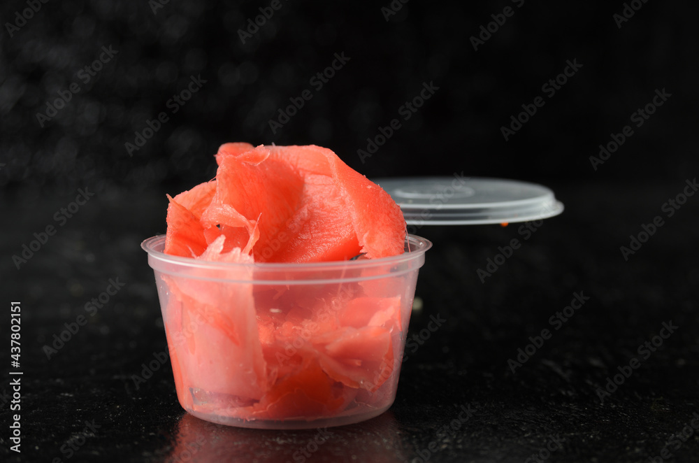 Ginger root chopped into thin slices of red color in a delivery plastic jar. Ginger root chopped into thin slices of red color in a delivery plastic jar.