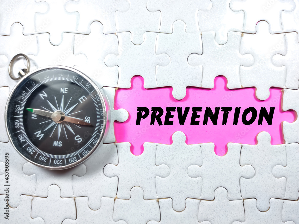 Selective focus.Text PREVENTION with compass and jigsaw puzzle on pink background.