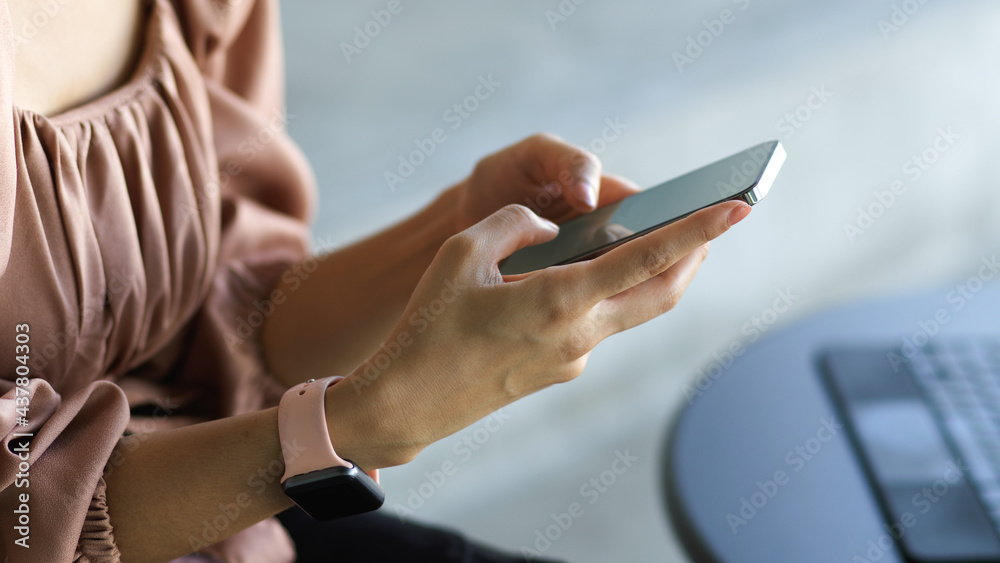 Side view of female worker hands texting message on smartphone