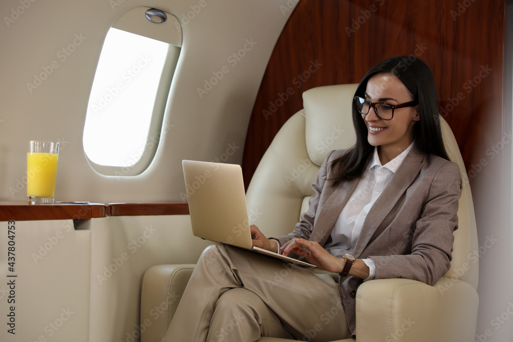 © New Africa - Businesswoman working on laptop in airplane during flight