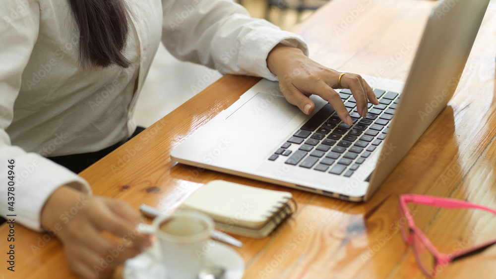 Businessperson hand working with laptop and holding coffee cup on workspace Businessperson hand working with laptop and holding coffee cup on workspace