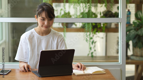 Portrait of young female student doing homework on digital tablet