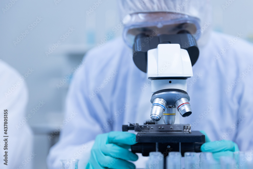 Close up Asian man scientist is wearing Personal Protective Equipment (PPE) Looking sample blood with Microscope doing experiment about coronavirus vaccine in laboratory. Medical experiment concept. Close up Asian man scientist is wearing Personal Protective Equipment (PPE) Looking sample blood with Microscope doing experiment about coronavirus vaccine in laboratory. Medical experiment concept.