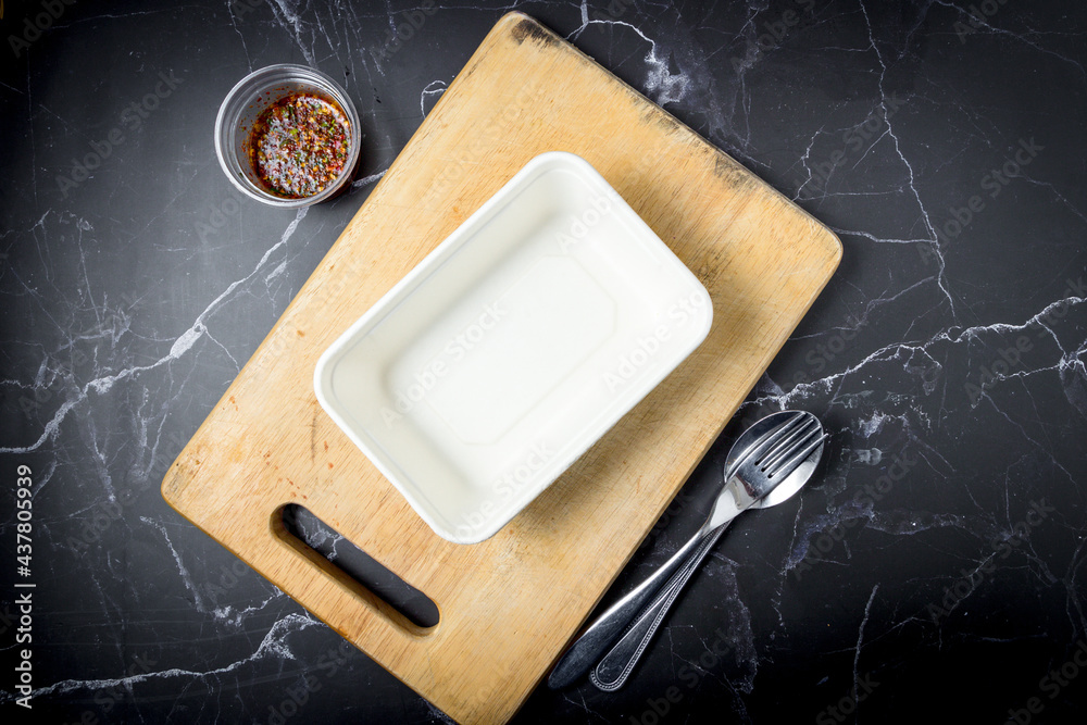 Empty rice box was placed on a cutting board with cutlery and dipping ...
