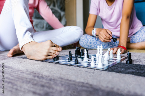 latin girl with cerebral palsy playing with her family holding a Chess piece with her foot at Home in disability concept in latin America