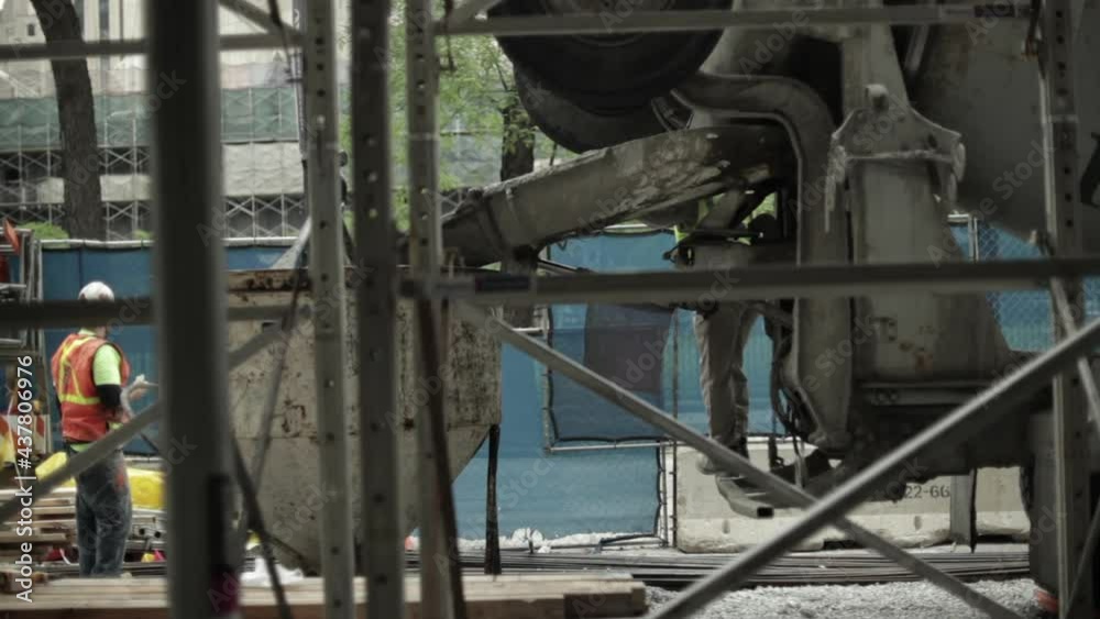 Two construction workers overseeing the pouring of concrete from a cement truck. Two construction workers overseeing the pouring of concrete from a cement truck.