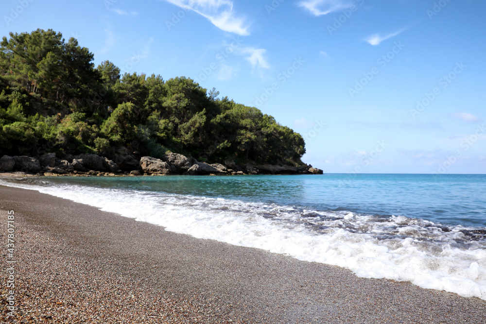 Beautiful sea beach near rocky hill with forest on sunny summer day Beautiful sea beach near rocky hill with forest on sunny summer day