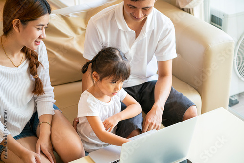 Happy Asian family using laptop computer for online learning a homeschooling in home living room during corona virus pandemic. homeschooling and Asian family concept