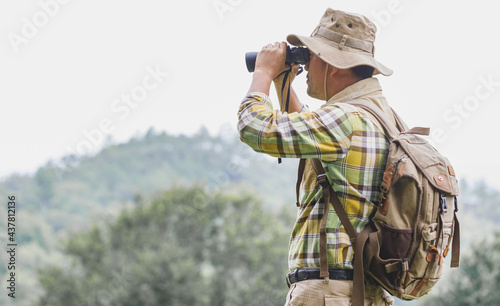 Hikers with backpacks holding binoculars looking on mountain forest