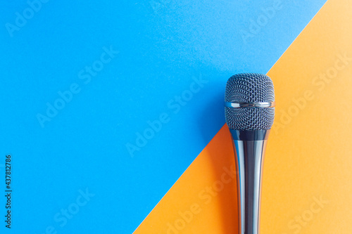 Microphone on a colorful blue and orange geometric background close up. Singing, writing music, karaoke online, creativity, vocals concept, symbol. Singing lessons