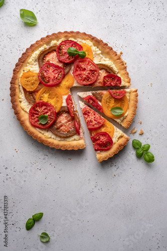 Quiche with colorful tomatoes, riccota, cream cheese and small basil leaves photo