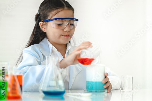 Cute little girl student child learning research and doing a chemical experiment while making analyzing and mixing liquid in glass at science class in school.Education and science concept © Art_Photo