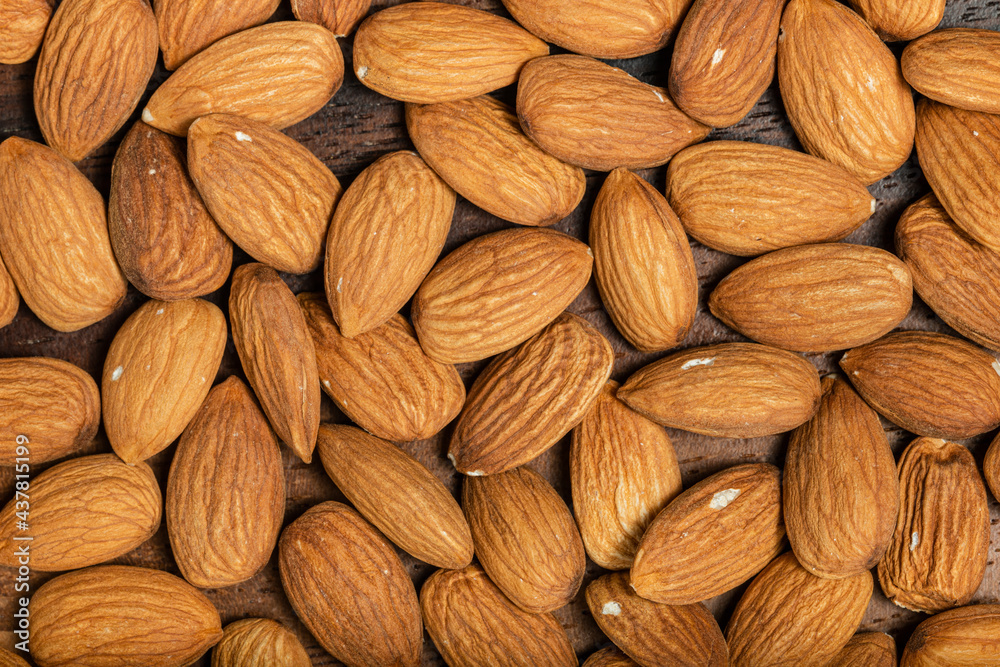 Fototapeta premium Background of big raw peeled almonds situated arbitrarily. Top view. Macro photography.