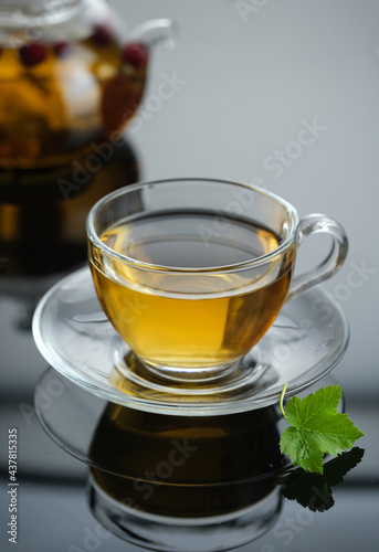 Yellow herbal tea in glass cup with leaf. Close-up cup of freshly brewed hot tea.