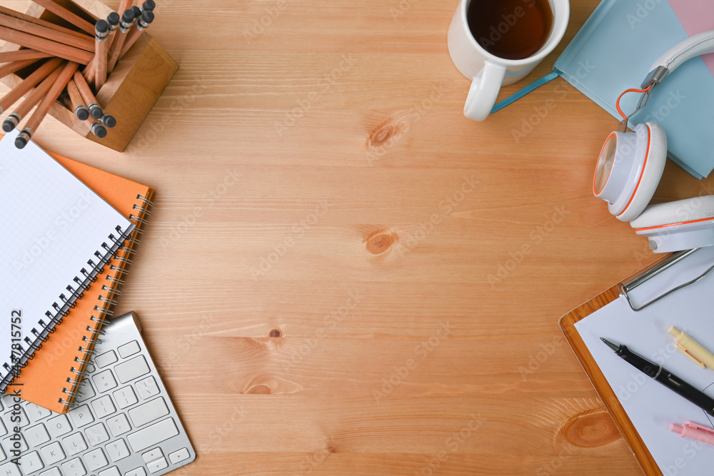 Above view of designer workspace with headphone, pencil holder, coffee cup and notebook on wooden desk.