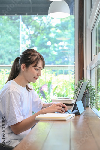 Side view young woman sitting in coffee shop and using computer tablet. Free Download Side view young woman sitting in coffee shop and using computer tablet. - GFXLoad