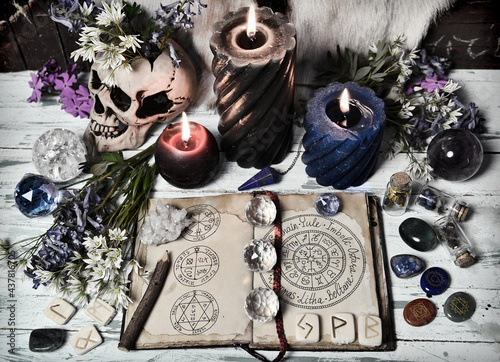 Grunge still life with open witch book, crystal, flowers, burning candles on altar table.