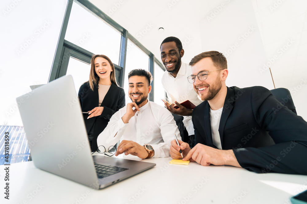 Group of multiracial IT professionals are working gathered behind a laptop