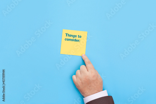 The businessman points to a sticky note with the inscription Things To Consider