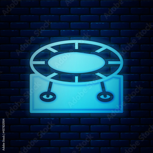 Glowing neon Jumping trampoline icon isolated on brick wall background. Vector