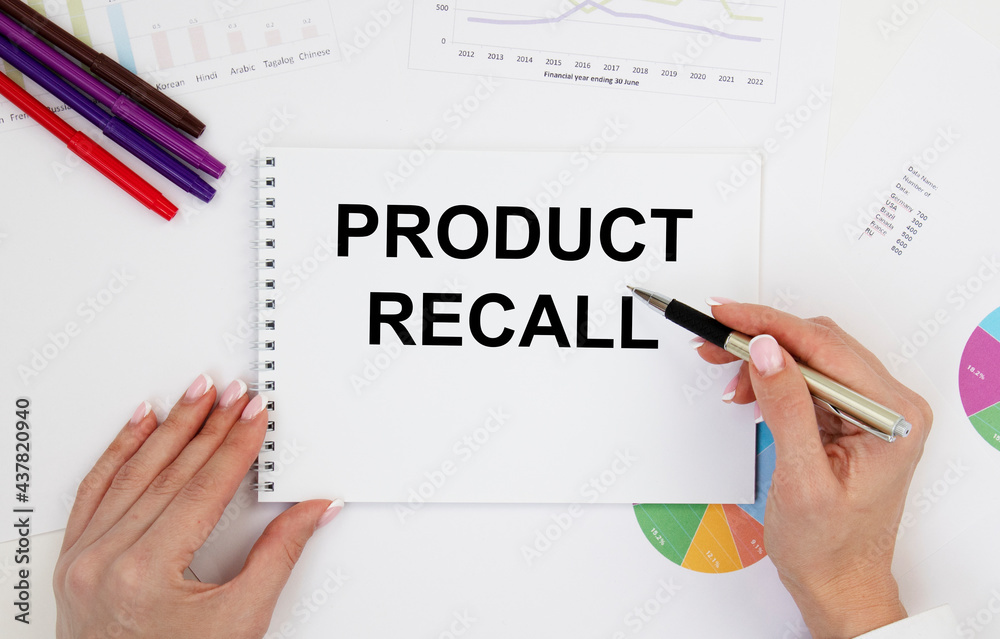 The girl holds a notebook in front of her with the text Product Recall, next to pencils and diagrams. The girl holds a notebook in front of her with the text Product Recall, next to pencils and diagrams.