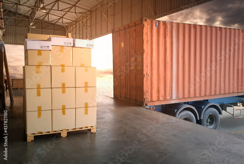 Stack of Package Boxes with Cargo Container. Trailer Truck Parked Loading at Dock Warehouse. Delivery Service. Shipping Warehouse Logistics. Cargo Shipment.  Freight Truck Transportation.	