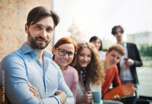 Portrait of young businessman with group of entrepreneurs indoors in office, looking at camera.