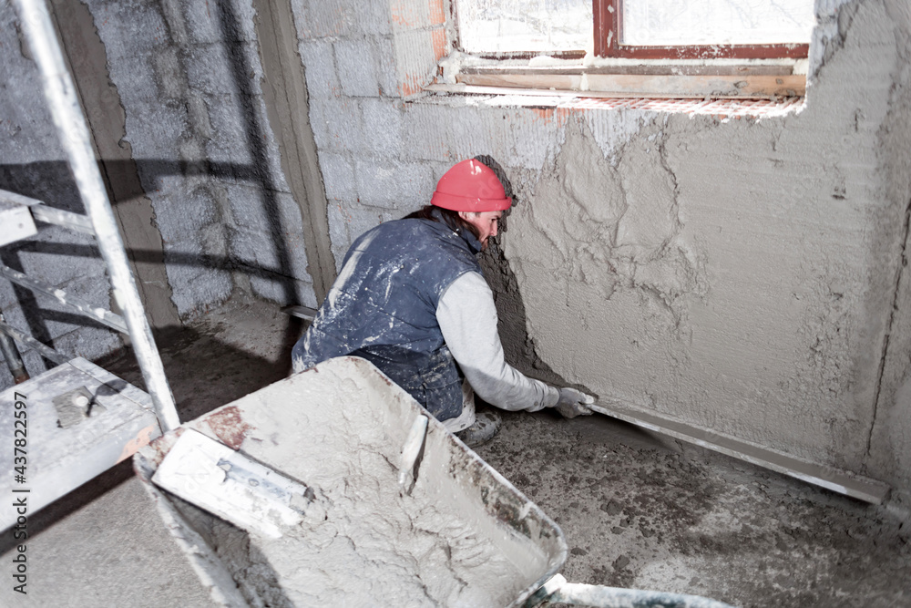 Real construction worker working on a wall inside the new house. Real construction worker working on a wall inside the new house.