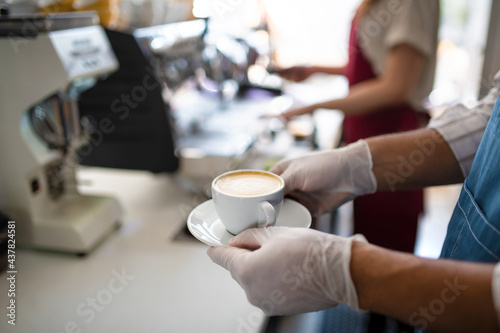 Obscured waiter serving coffee in cafe, small business, coronavirus and new normal concept.