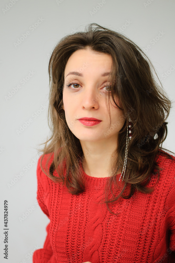 Studio portrait of young woman in red knitted sweater and earring on white background Studio portrait of young woman in red knitted sweater and earring on white background