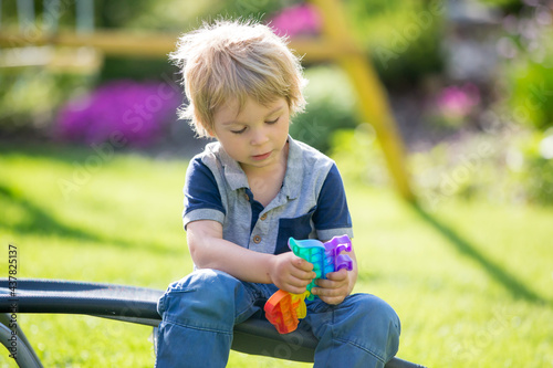 Blond child, playing with a pop up toy in the garden, antistrees silicone toy photo