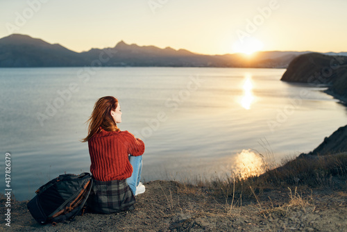 a traveler in a sweater Sits on the seashore and watches the sunset