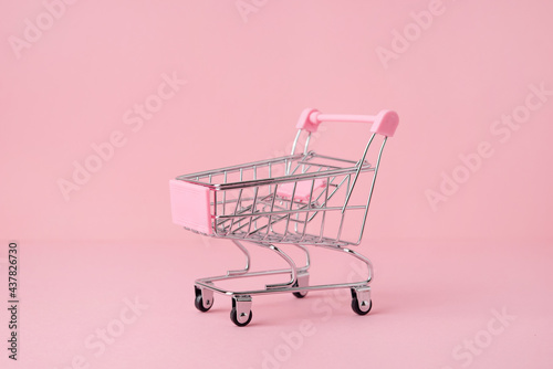 Small shopping market trolley on a pink background, copy space, shopping concept
