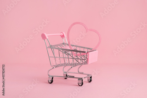 Small shopping market trolley on a pink background, copy space, shopping and love concept