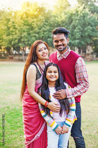 Beautiful Indian family with 10-year-old daughter standing together in a park © Mila Supinskaya 