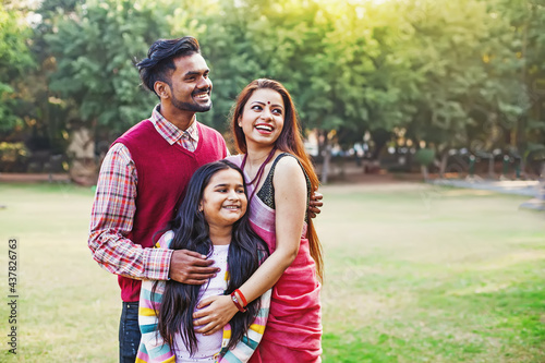 Beautiful Indian family with 10-year-old daughter standing together in a park