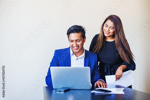 Two Indian colleagues working on the project, using laptop in the office
