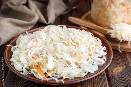 Pickled sauerkraut with carrots on a wooden table.