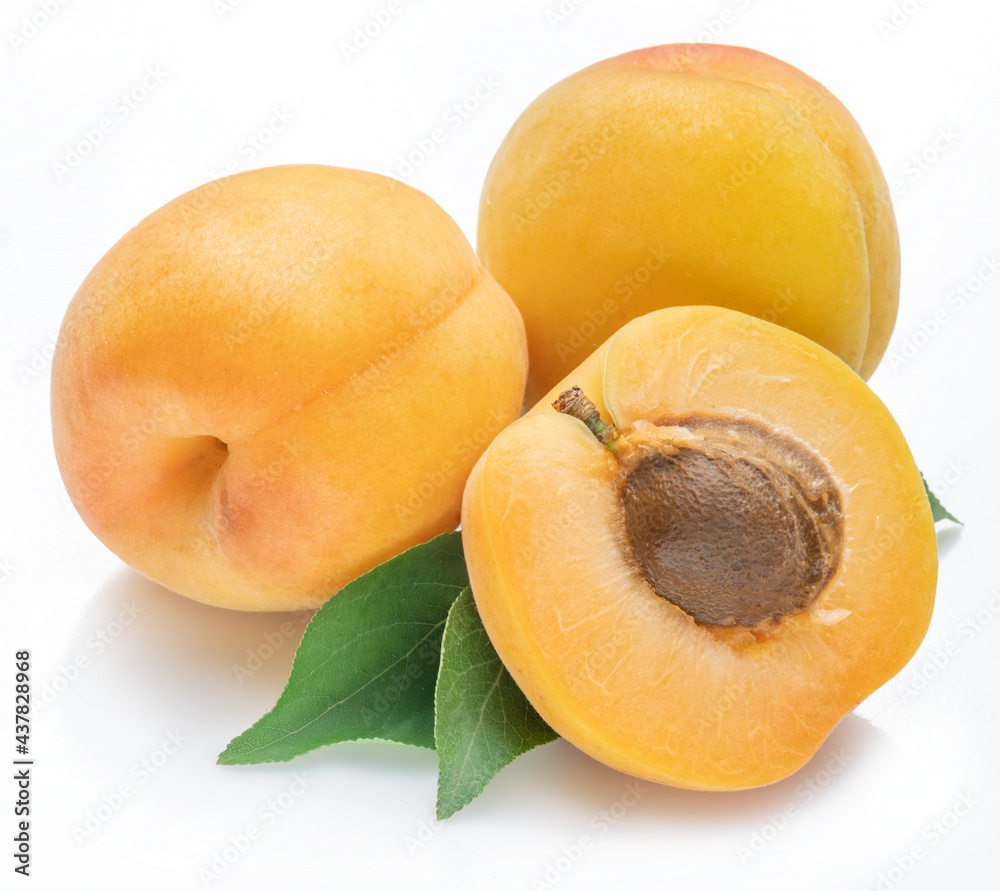 Ripe apricots with leaves isolated on white background.