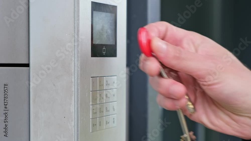 Male using intercom at residential building entrance. opens electronic code lock. man hand entering security system code, pressing button with index finger intercom device entrence door. photo