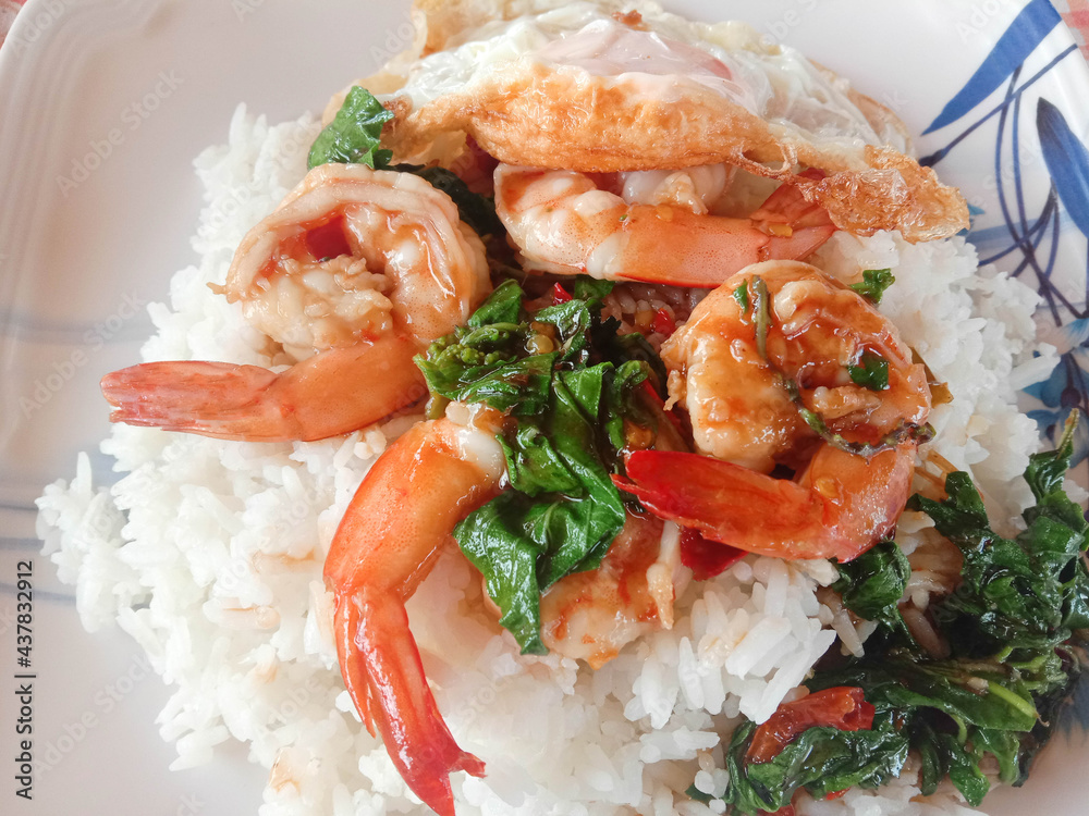 Stir-Fried Basil with Shrimp and Rice with Fried Egg on the dish, Thai delicious food isolated on wooden background closeup. Stir-Fried Basil with Shrimp and Rice with Fried Egg on the dish, Thai delicious food isolated on wooden background closeup.