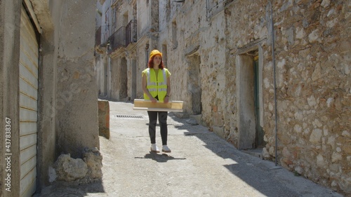 Giovane ragazza ingegnere con caschetto visita la città abbandonata fantasma