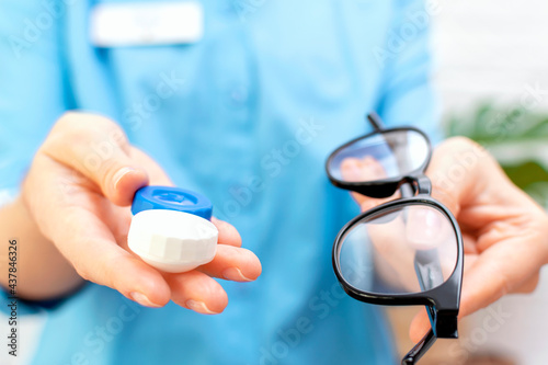 Woman doctor gives a pair of contact lenses in a case and glasses in her hand of choice to a patient in a clinic or optical store. Ophthalmology, vision correction and protection, eye health concept